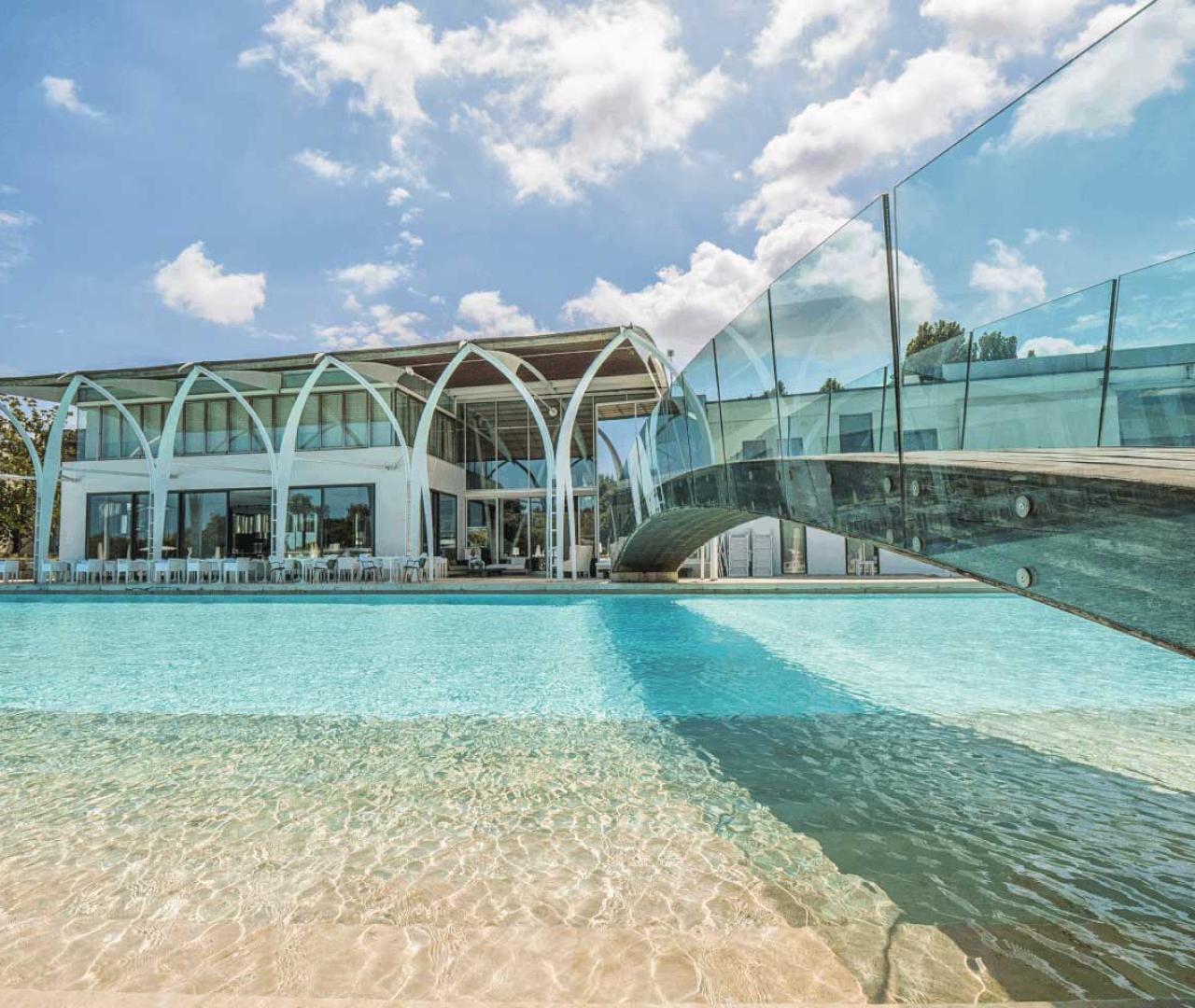 La piscina in pietra bianca incorniciata dagli archi del resort